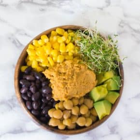 This taco hummus buddha bowl is easy to put together and is jammed packed with healthy ingredients: heaps of corn, beans, alfalfa sprouts, avocado, chickpeas, and hummus served over quinoa.