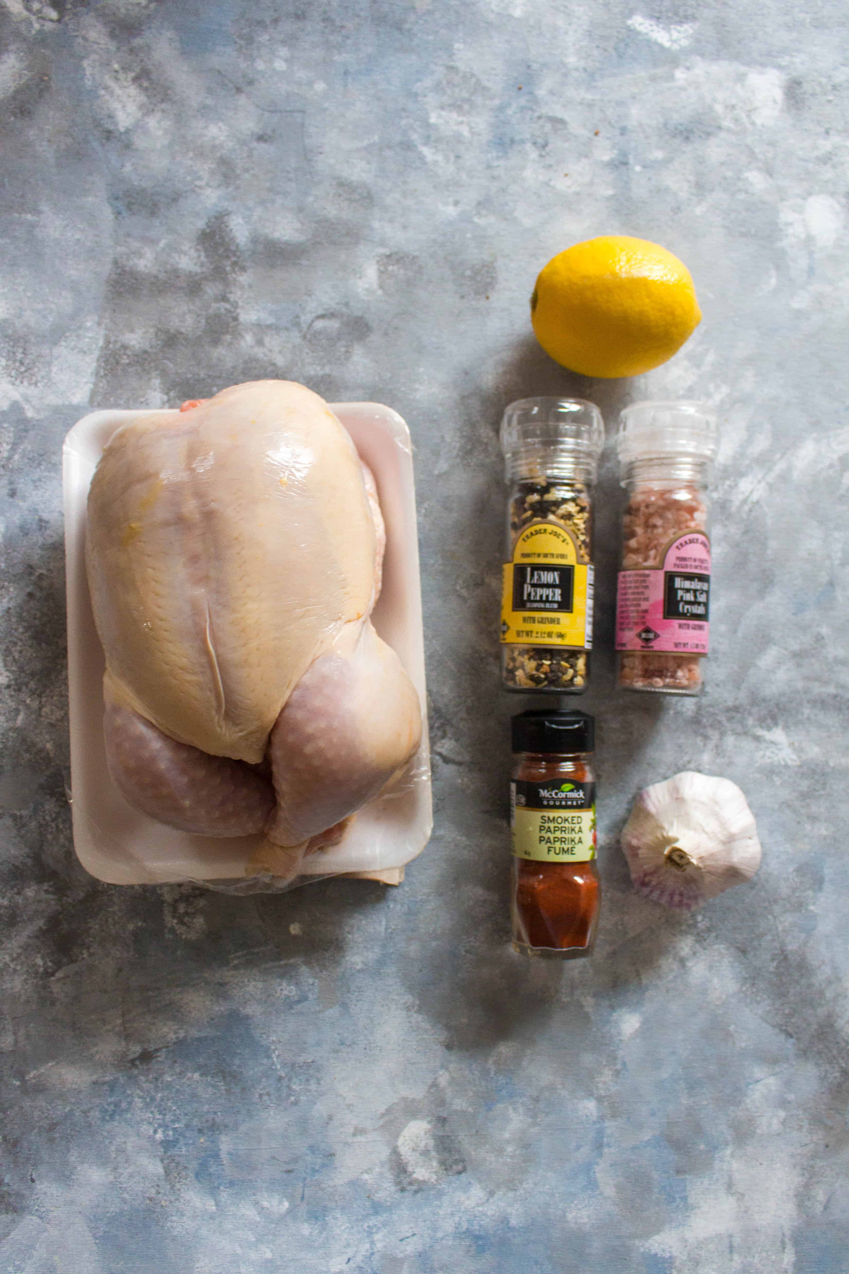 Ingredients for making a whole chicken in an Instant Pot: whole chicken, lemon, salt, pepper, paprika, garlic, lemon