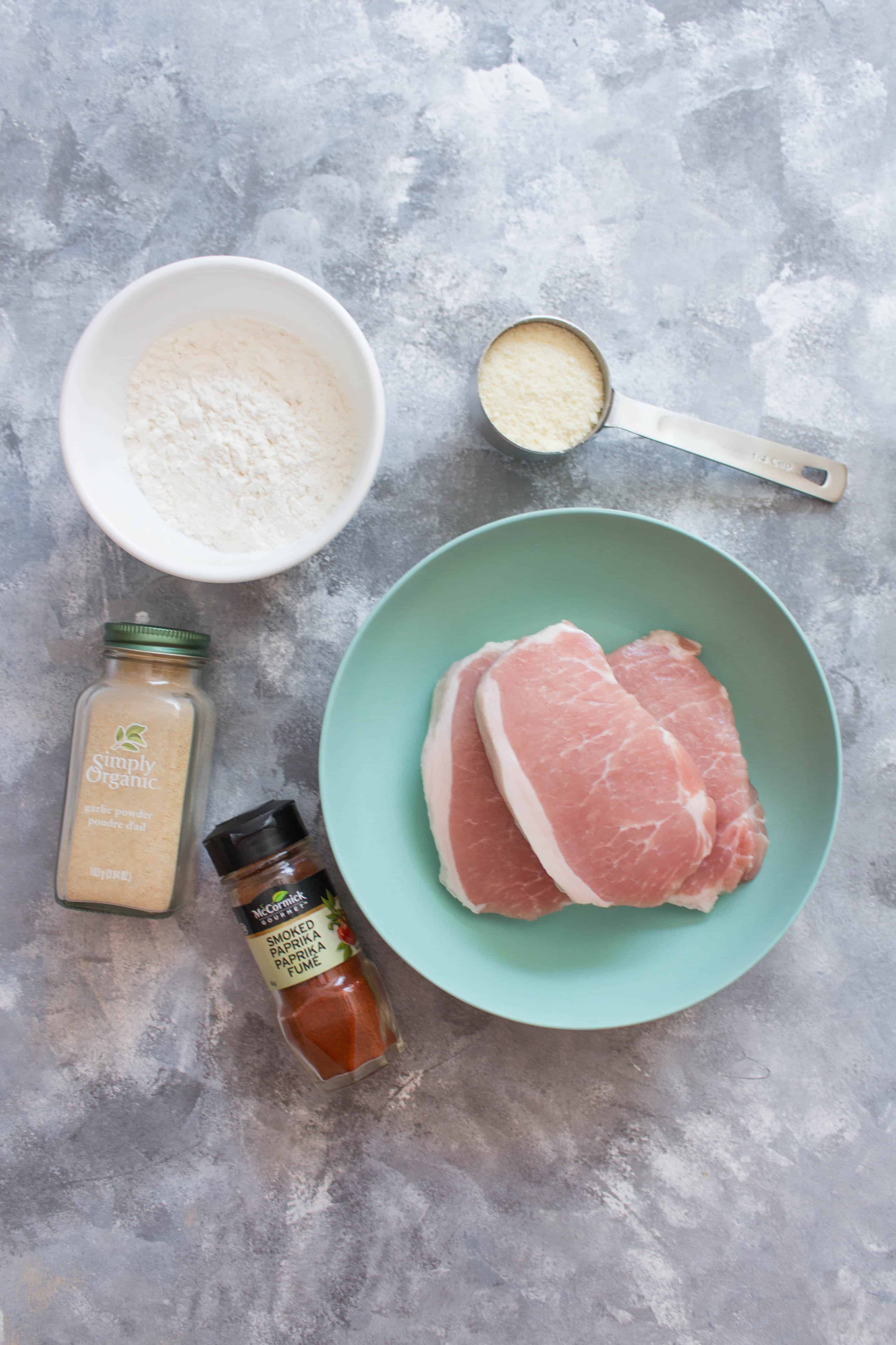 Flat lay of ingredients: flour, cheese, garlic, paprika, pork chops | These delicious Boneless Air Fryer Pork Chops are so moist on the inside and crispy on the outside! Done in less than 20 minutes, these pork chop are going to be your new go-to easy dinners!