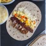 freezer friendly breakfast wraps laid down with ingredients (sausage, bacon, cheese, egg, bell peppers) shown