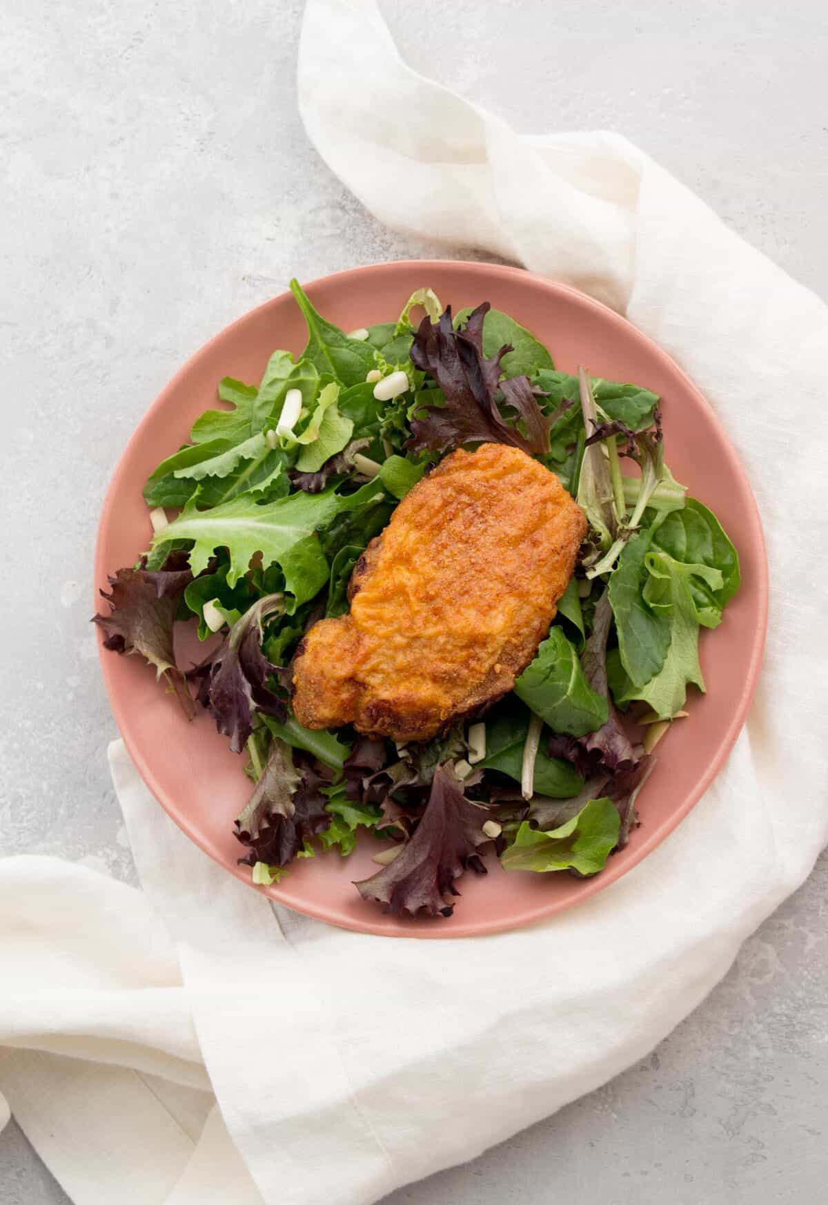 air fryer boneless pork chop on a plate of salad.