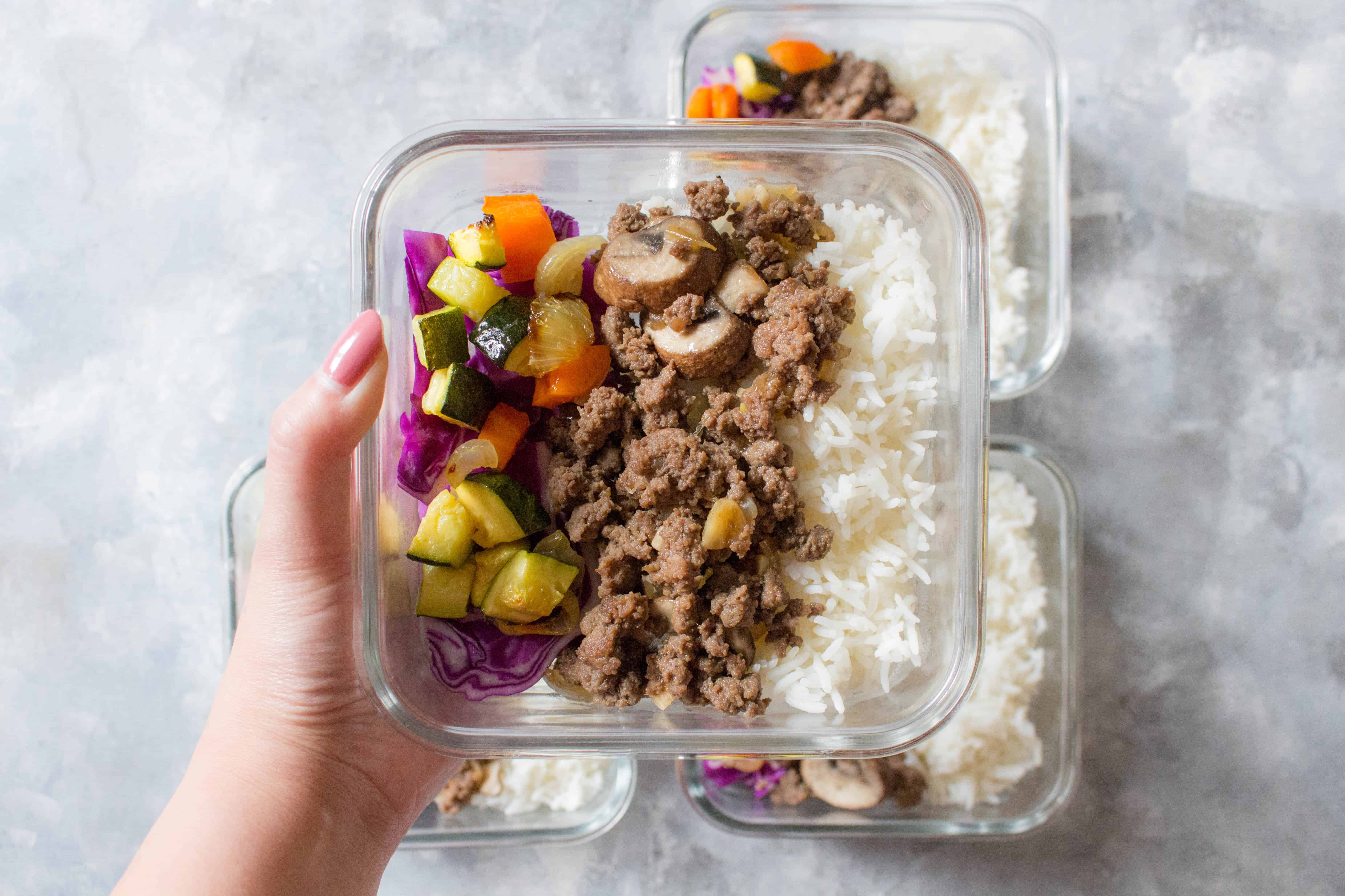 A hand holding up a Korean beef bowl meal prep.