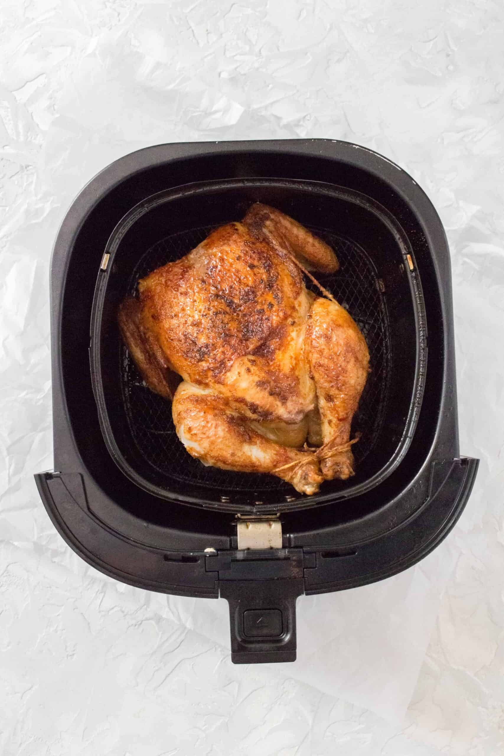 Overhead view of a whole chicken roasted in an air fryer.