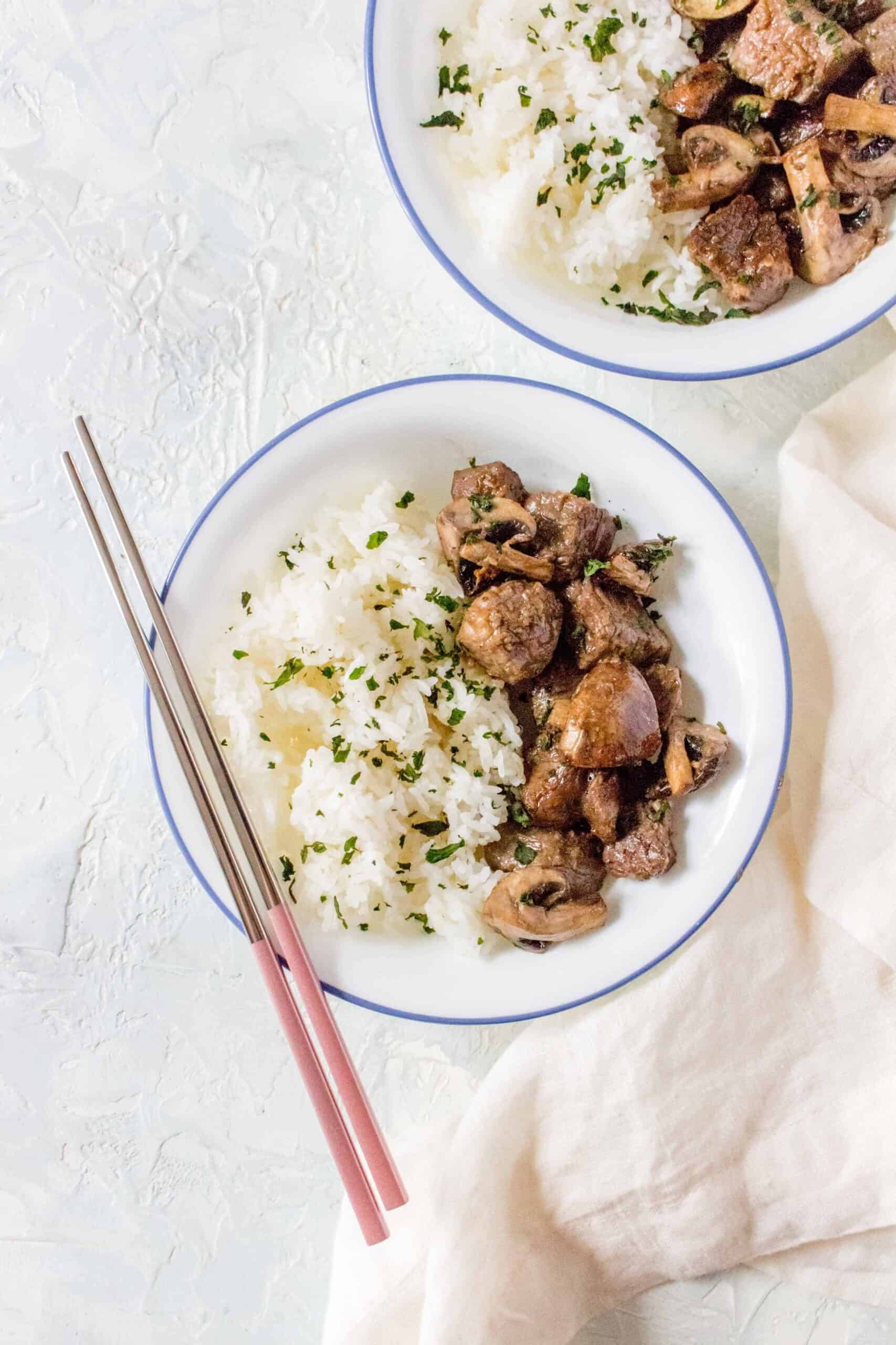 A plate with air fryer steak bites and mushrooms with jasmine rice.