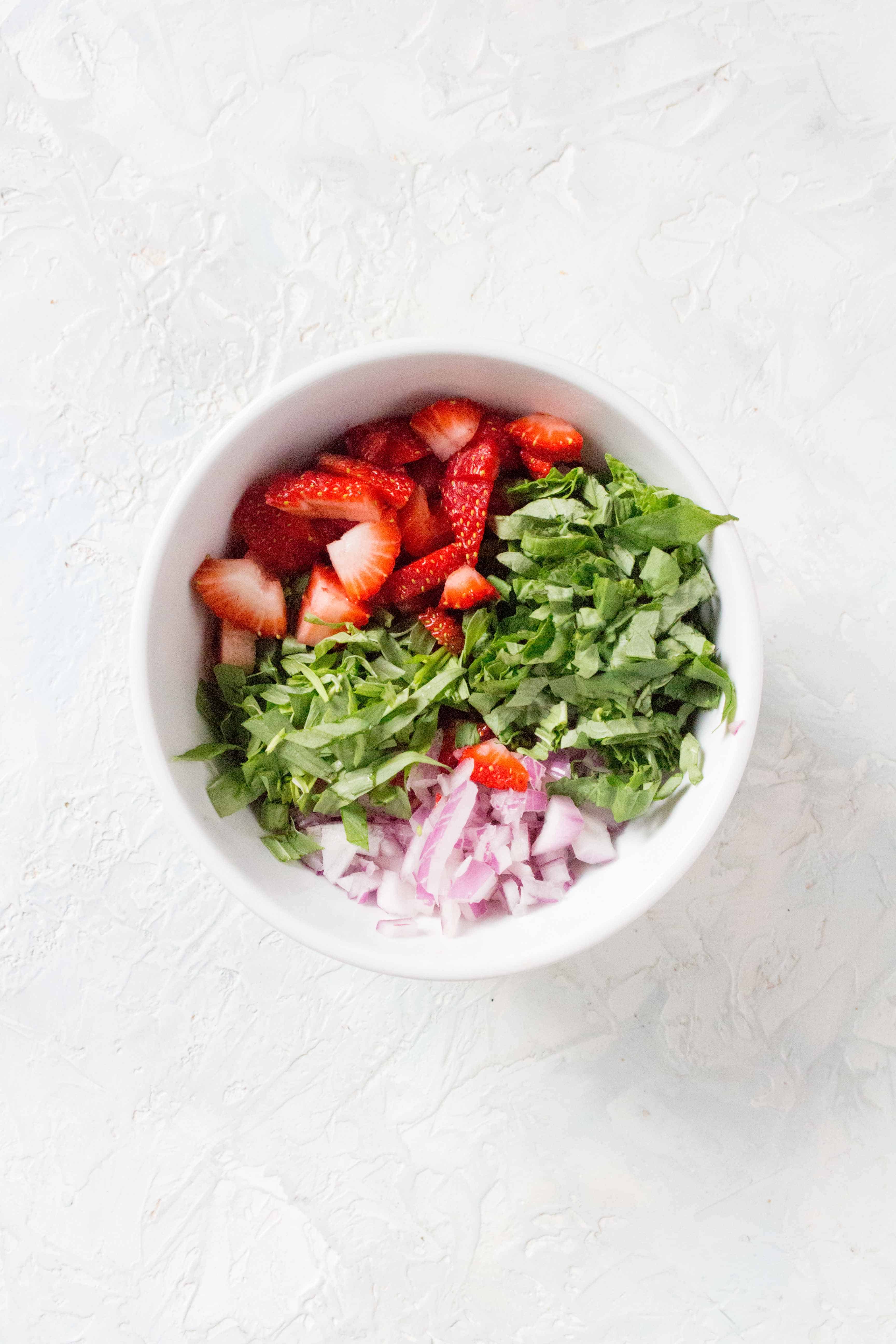 A bowl of ingredients for strawberry salsa.