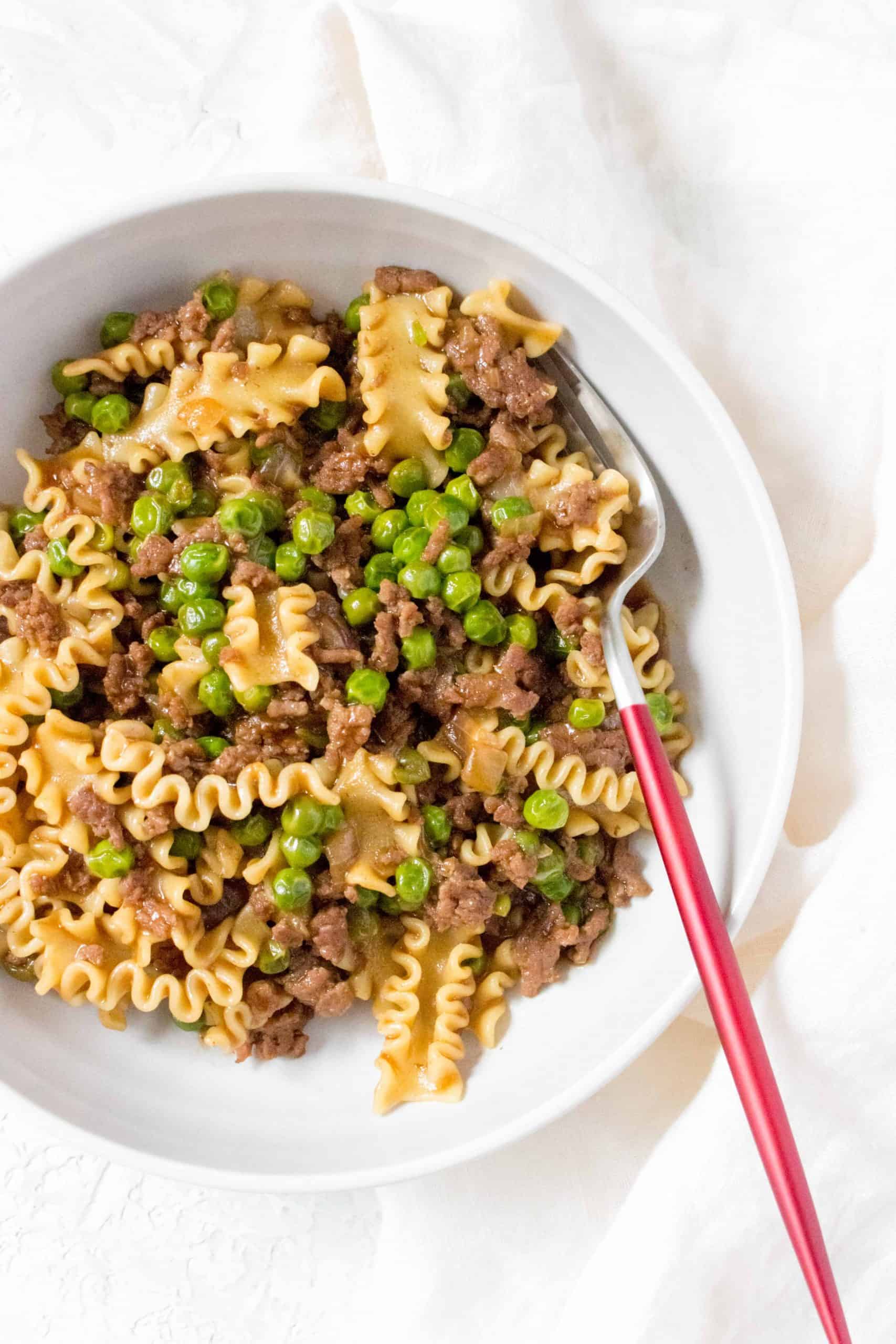 Close up of a bowl of mafalda pasta with beef and peas.