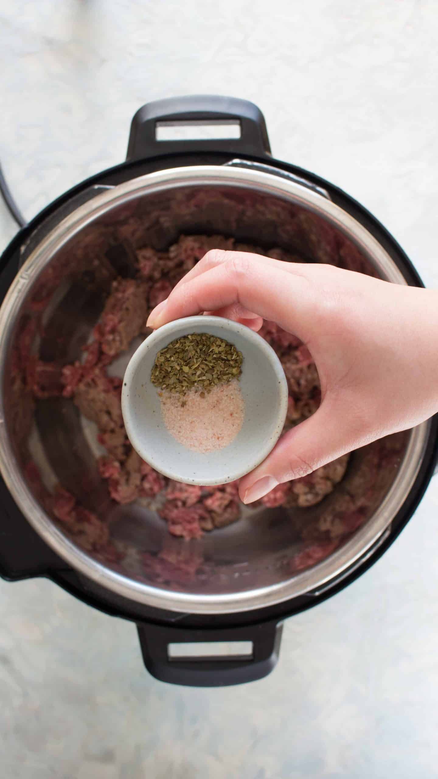 adding salt and oregano into beef for beef browning in instant pot for instant pot spaghetti 