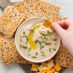 white bean hummus dip surrounded by crackers and cheese.
