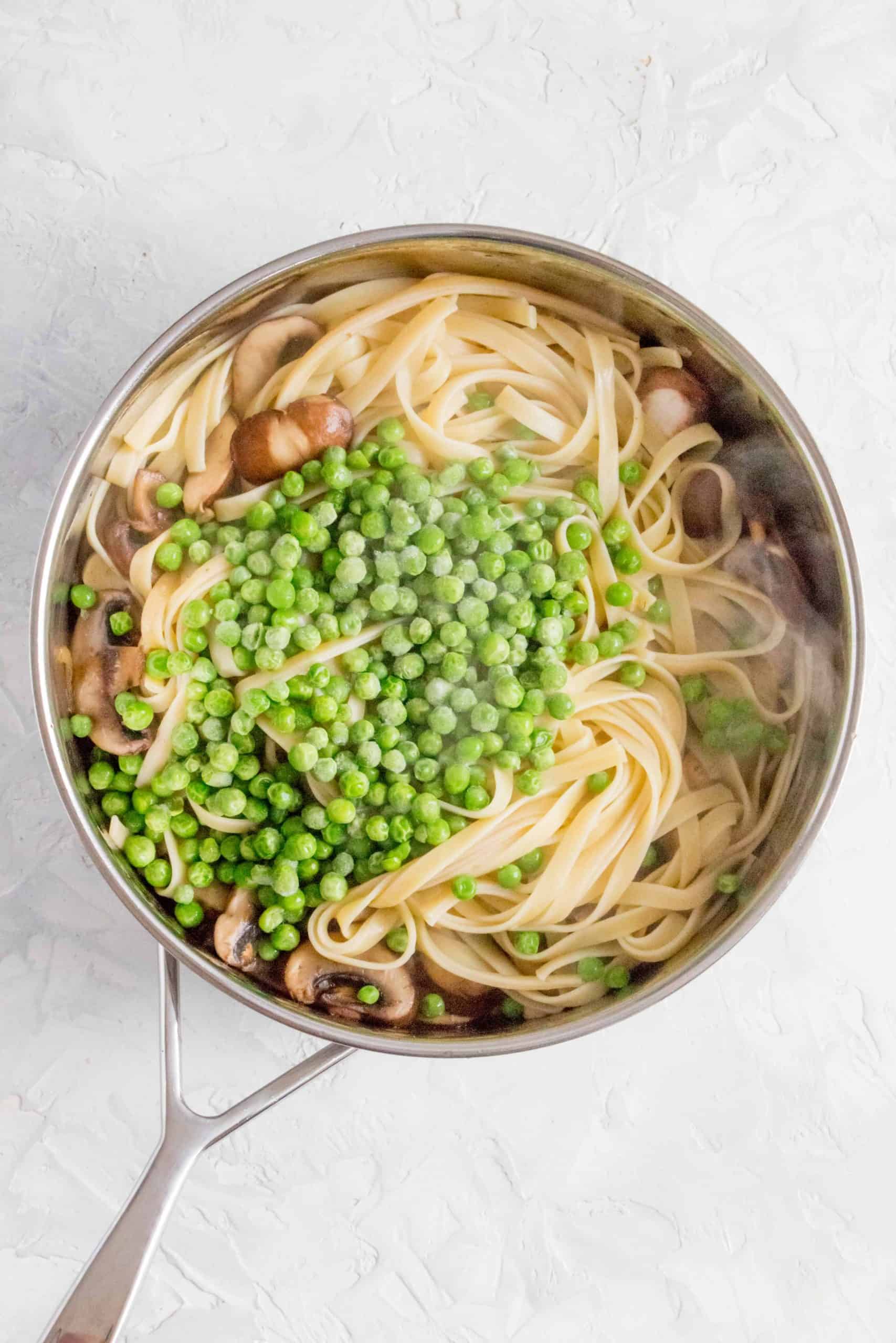 adding pasta and peas to the pan of shallots and mushrooms