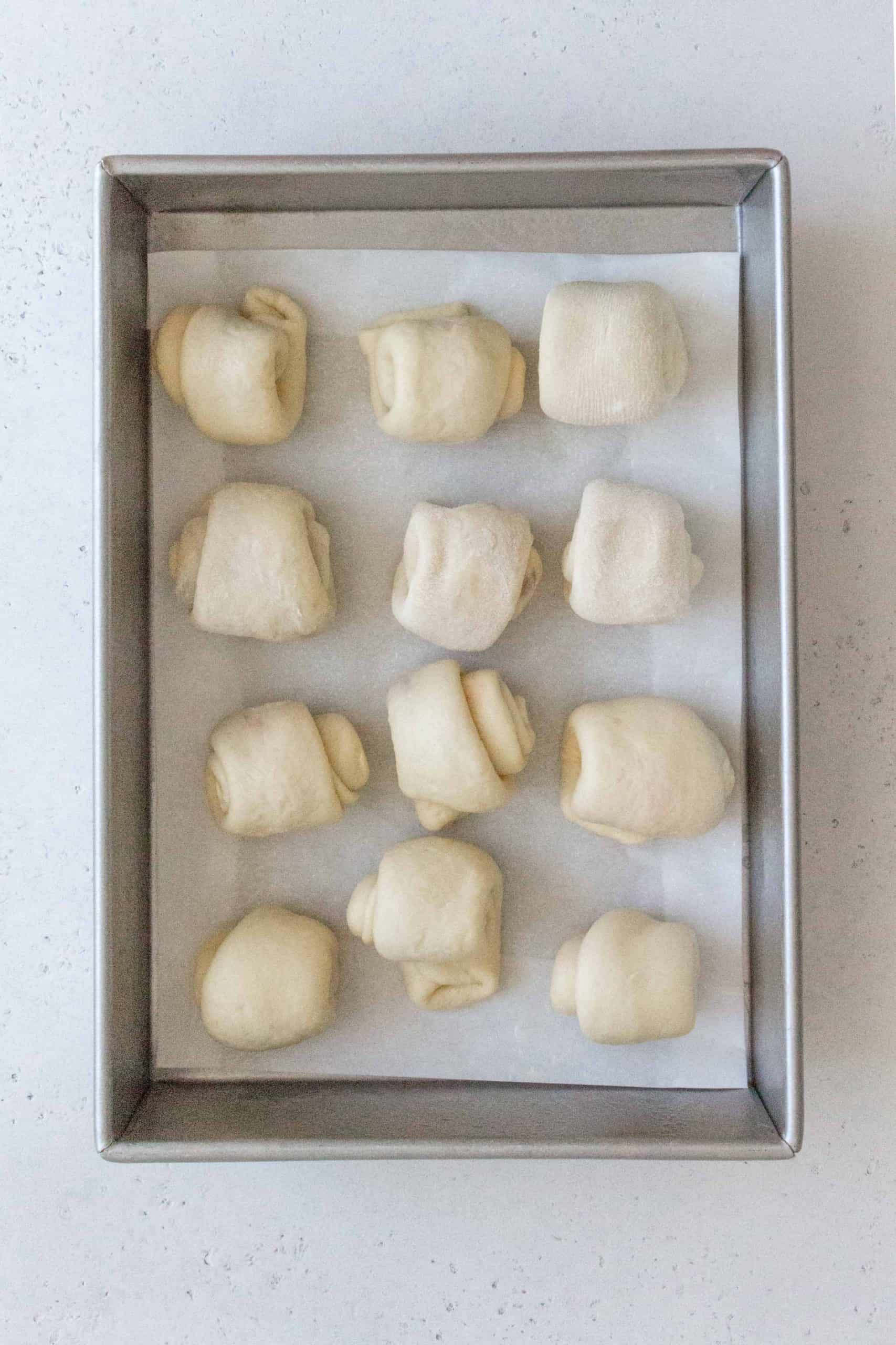 Place all the strawberry jam filled dinner rolls into a greased pan or parchment lined pan and proof again for 30-40 minutes.
