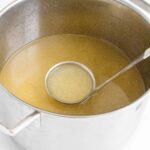 chicken broth in 6qt stock pot with ladle inside