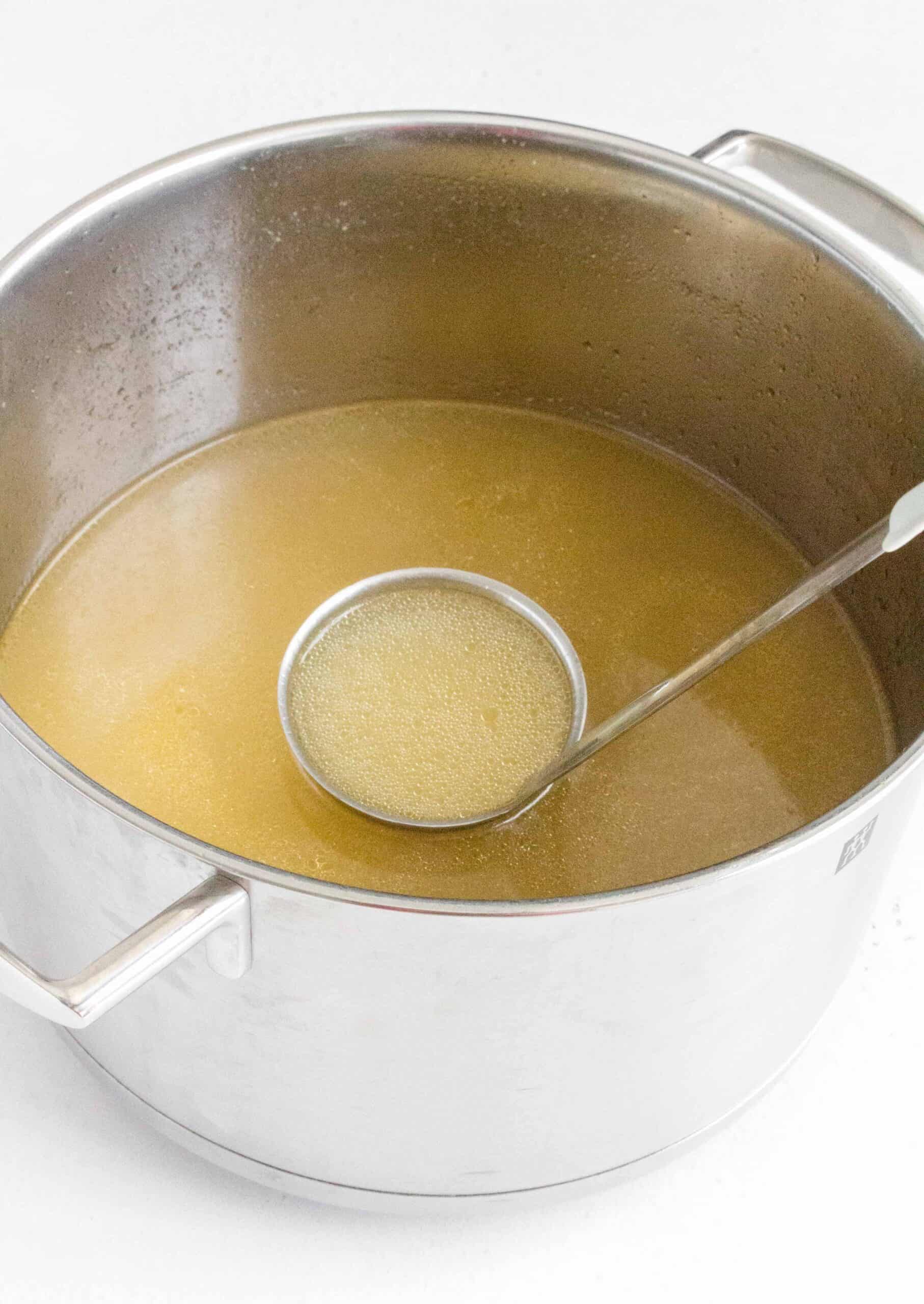 chicken broth in 6qt stock pot with ladle inside.