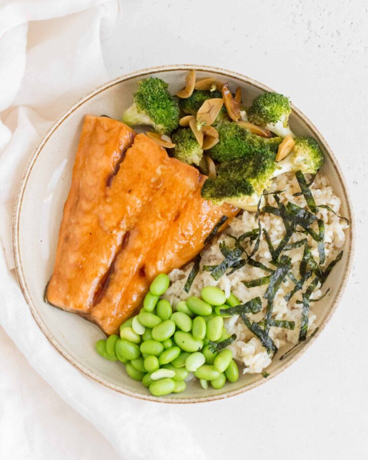 plate with teriyaki salmon with broccoli, edamame, brown rice, and seaweed