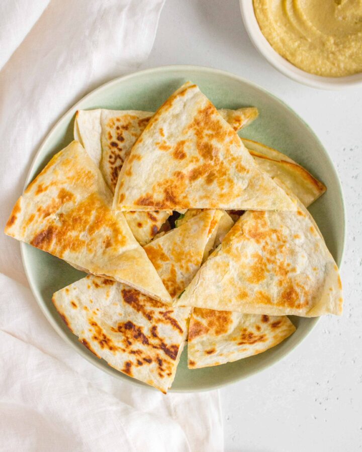 green plate with chicken and hummus quesadillas