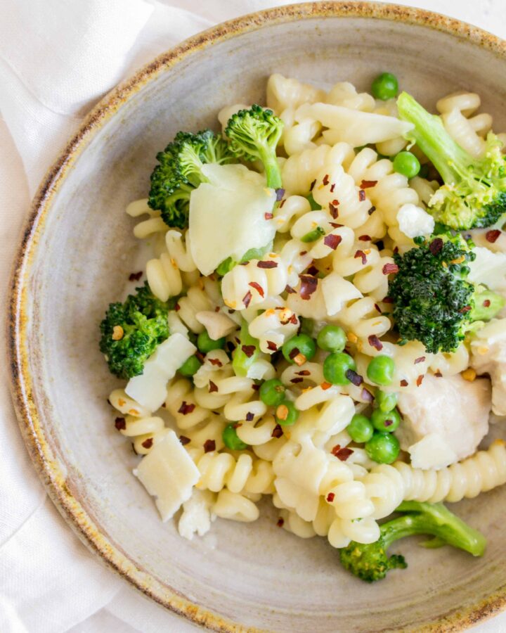 close up of a plate of pasta with broccoli peas red chili flakes