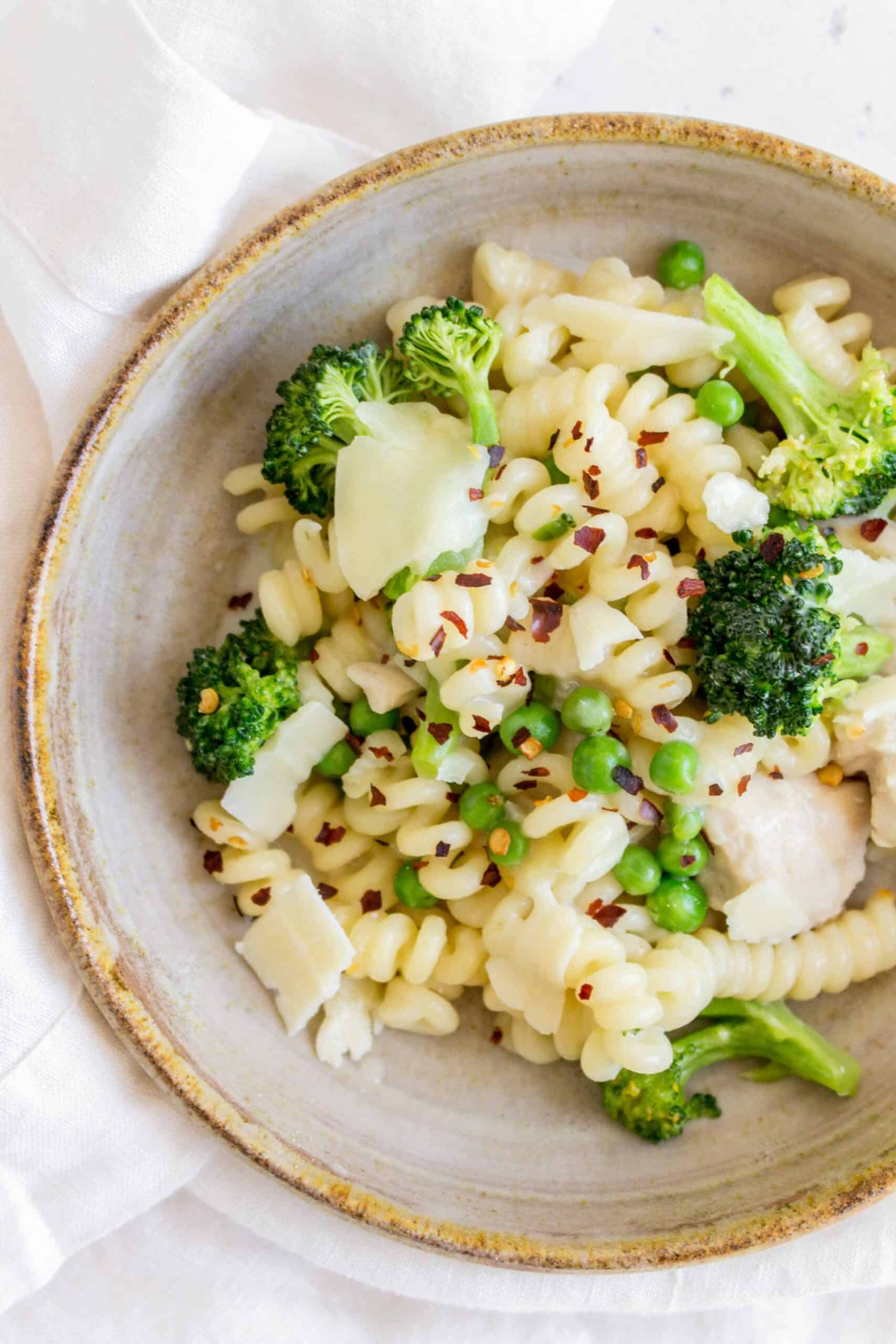 close up of a plate of pasta with broccoli peas red chili flakes