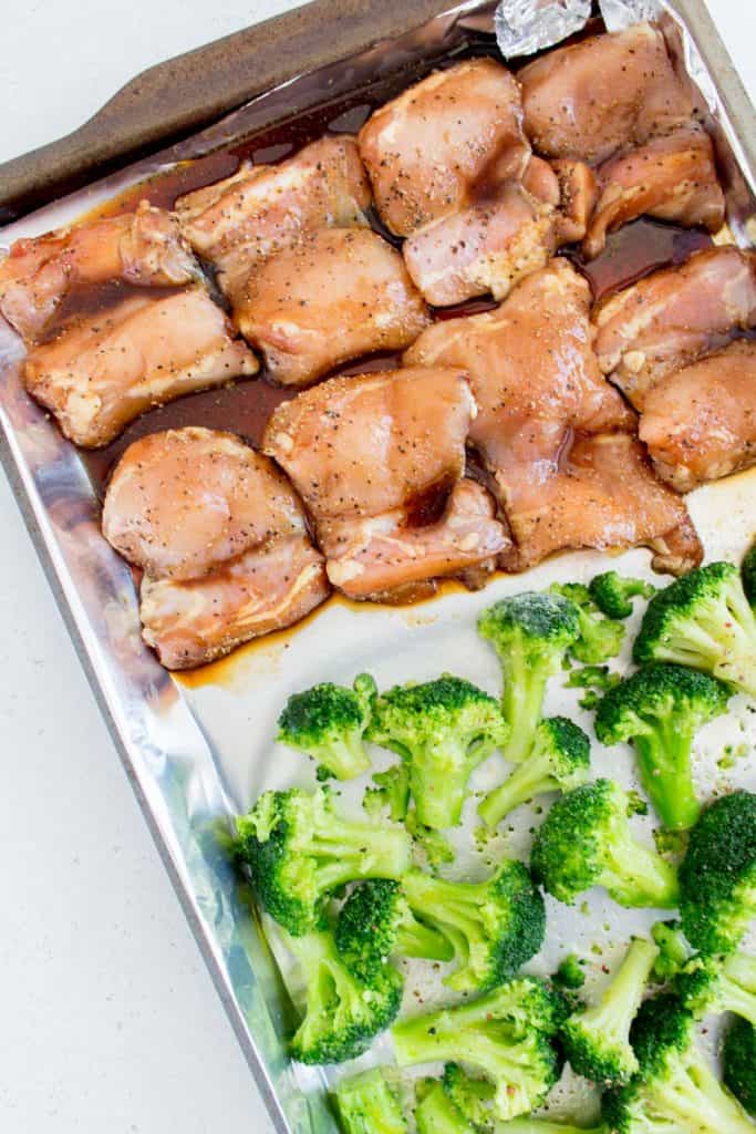 close up of honey black pepper chicken with broccoli in a sheet pan before baking