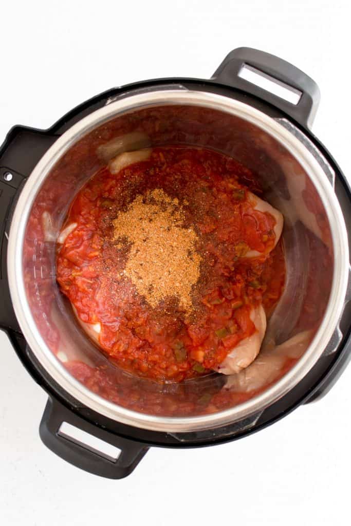 salsa and taco seasoning on top of chicken breasts in an instant pot