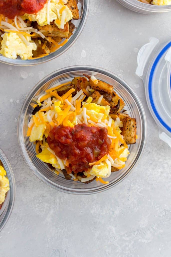 meal prep container with potatoes, eggs, cheese, and salsa