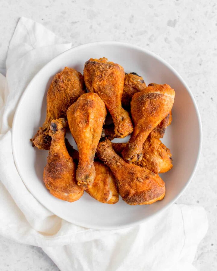 a white plate of crispy baked drumsticks