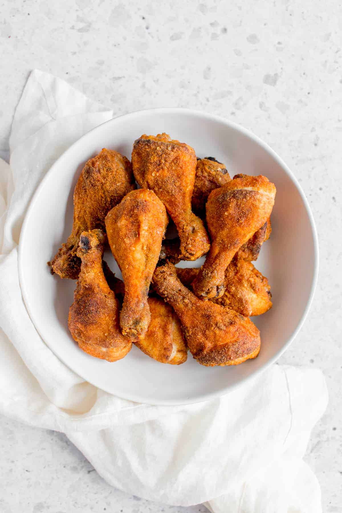 a white plate of crispy baked drumsticks