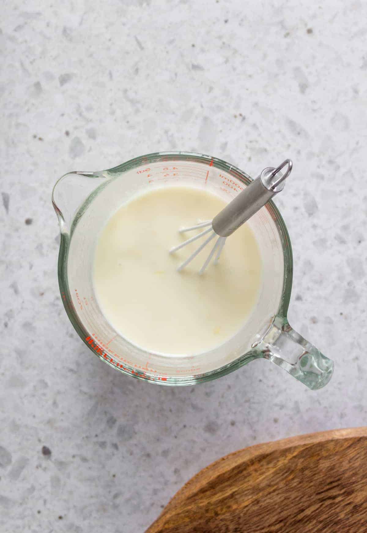 creamy lemon dressing in a measuring cup and a whisk