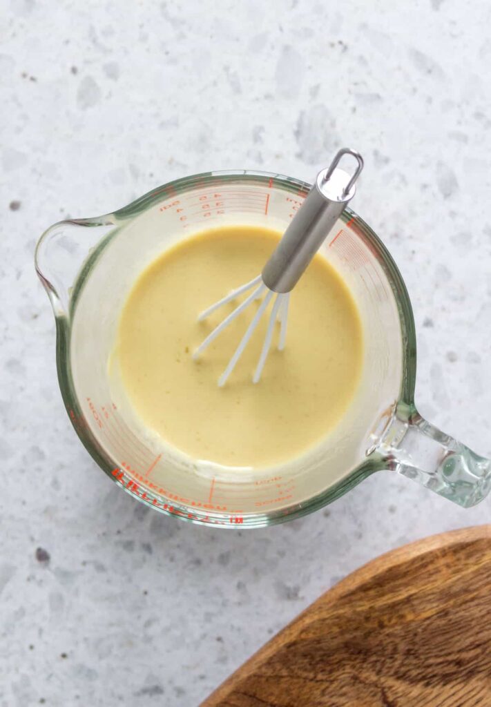 honey mustard dressing in a measuring cup with a whisk