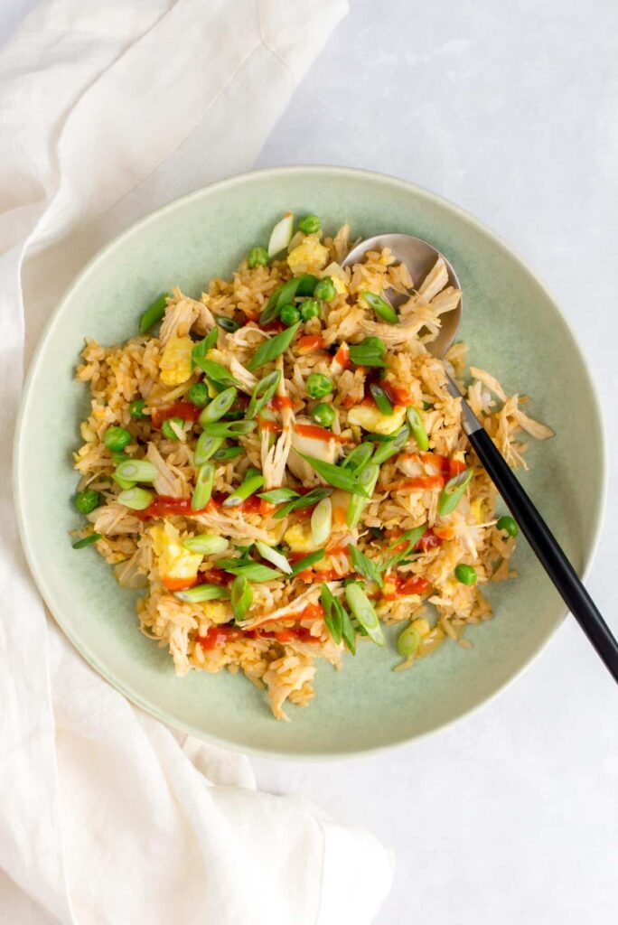 Bowl of chicken sriracha fried rice with a spoon.