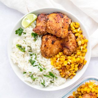 A white plate with chipotle chicken, caramelized corn, and cilantro lime rice.