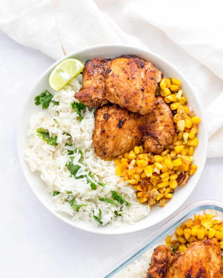 A white plate with chipotle chicken, caramelized corn, and cilantro lime rice.