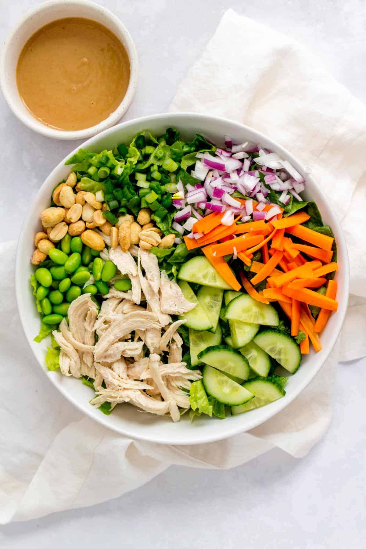 Bowl of thai chopped salad with a small bowl of peanut sauce beside it.