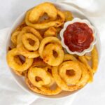 Onion rings in a plate with ketchup.