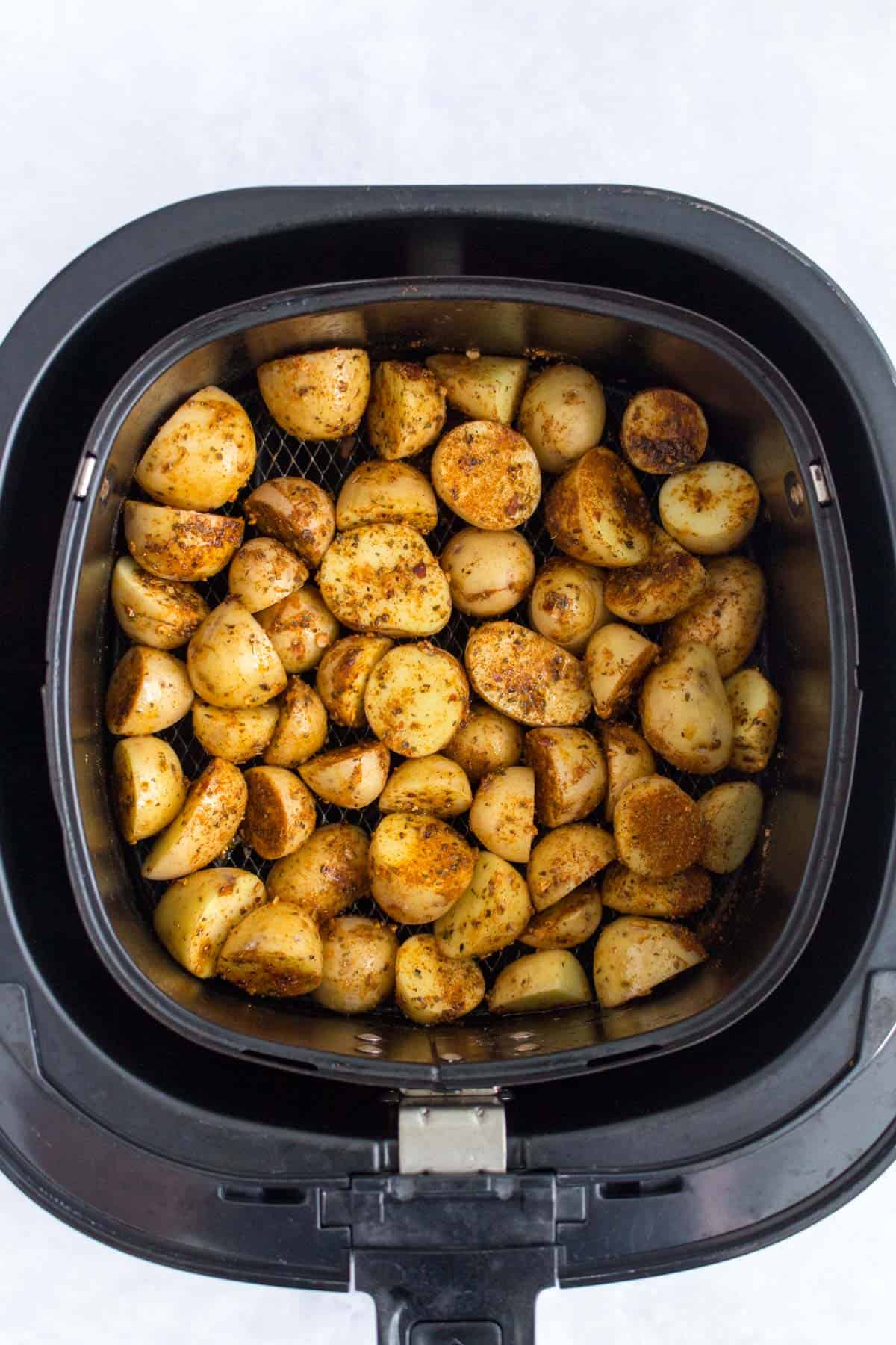 Baby potatoes in an air fryer before roasting.