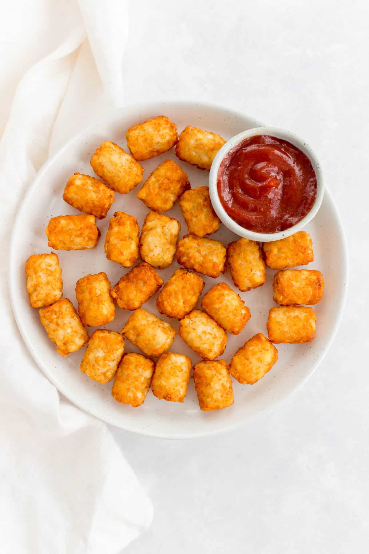 A plate of tater tots with ketchup.