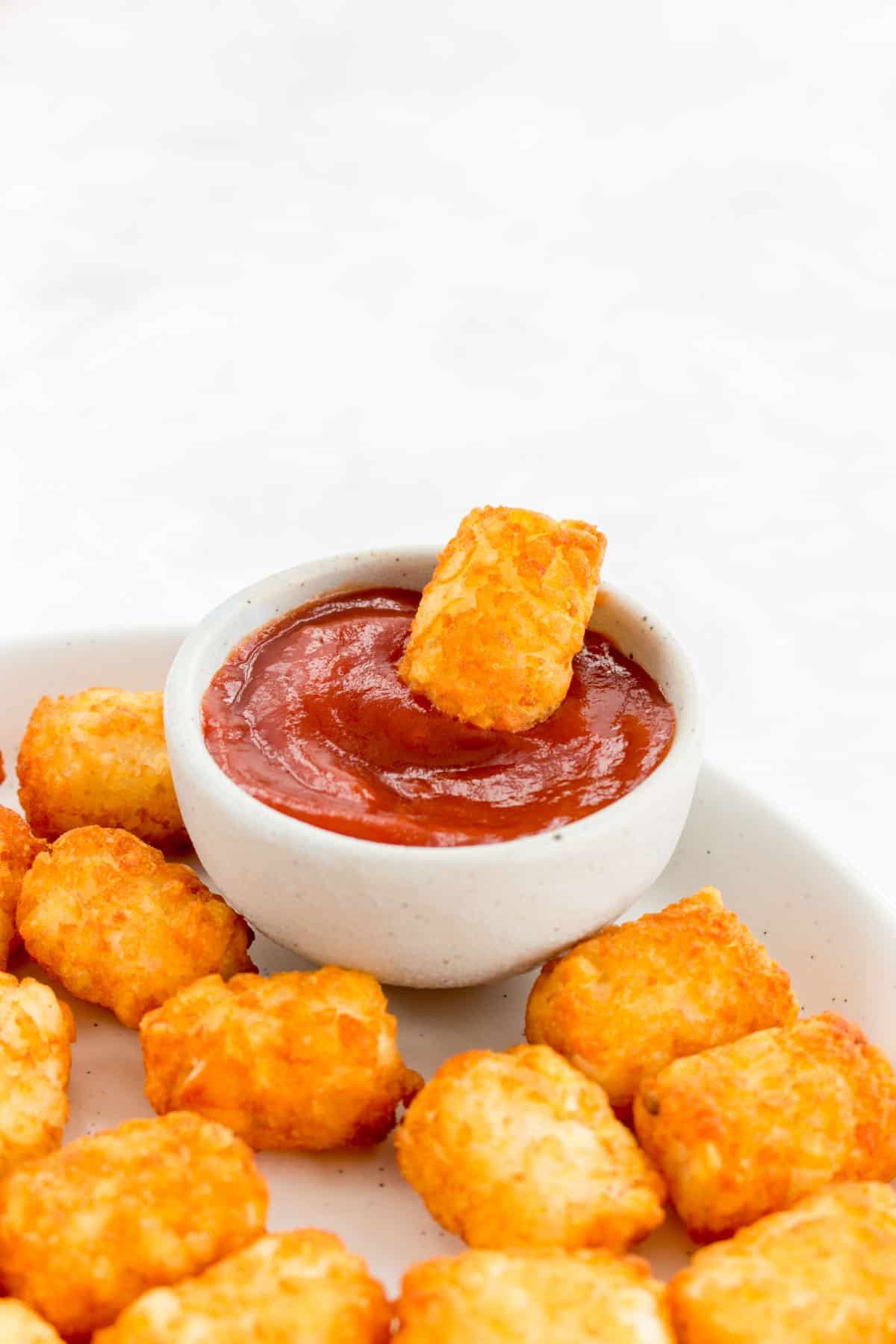 Air fryer tater tots dipped in ketchup.
