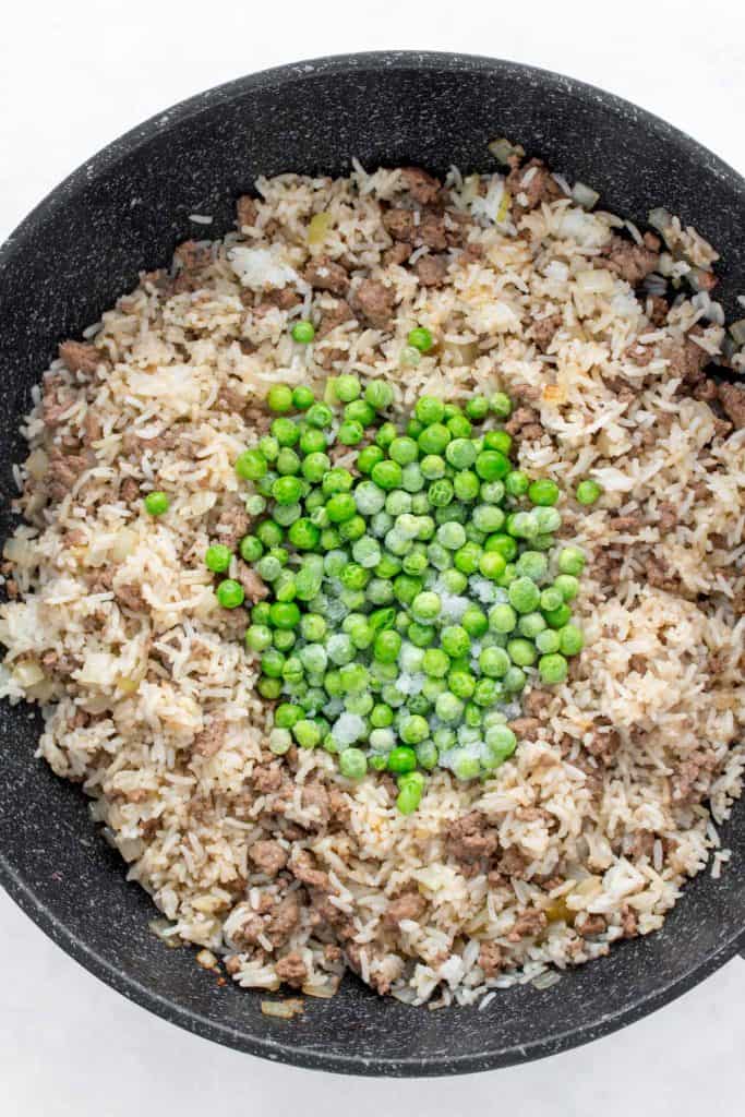 Adding frozen peas to beef fried rice.