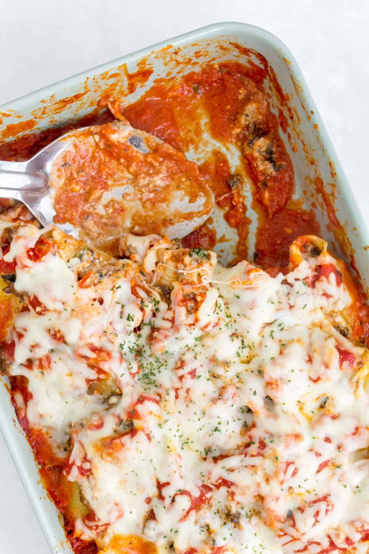 Casserole dish of stuffed shells with a serving spoon.