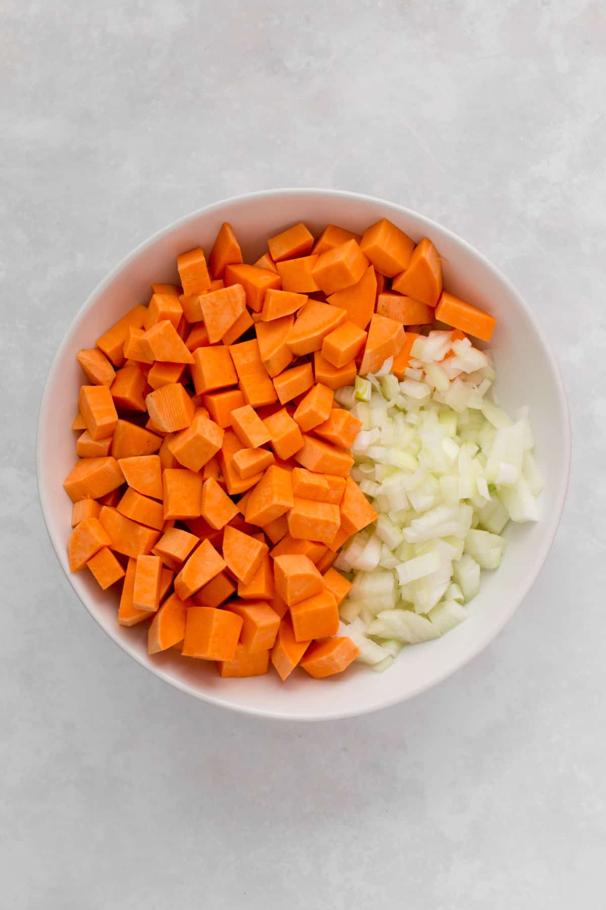 Bowl of diced sweet potatoes and diced onions.
