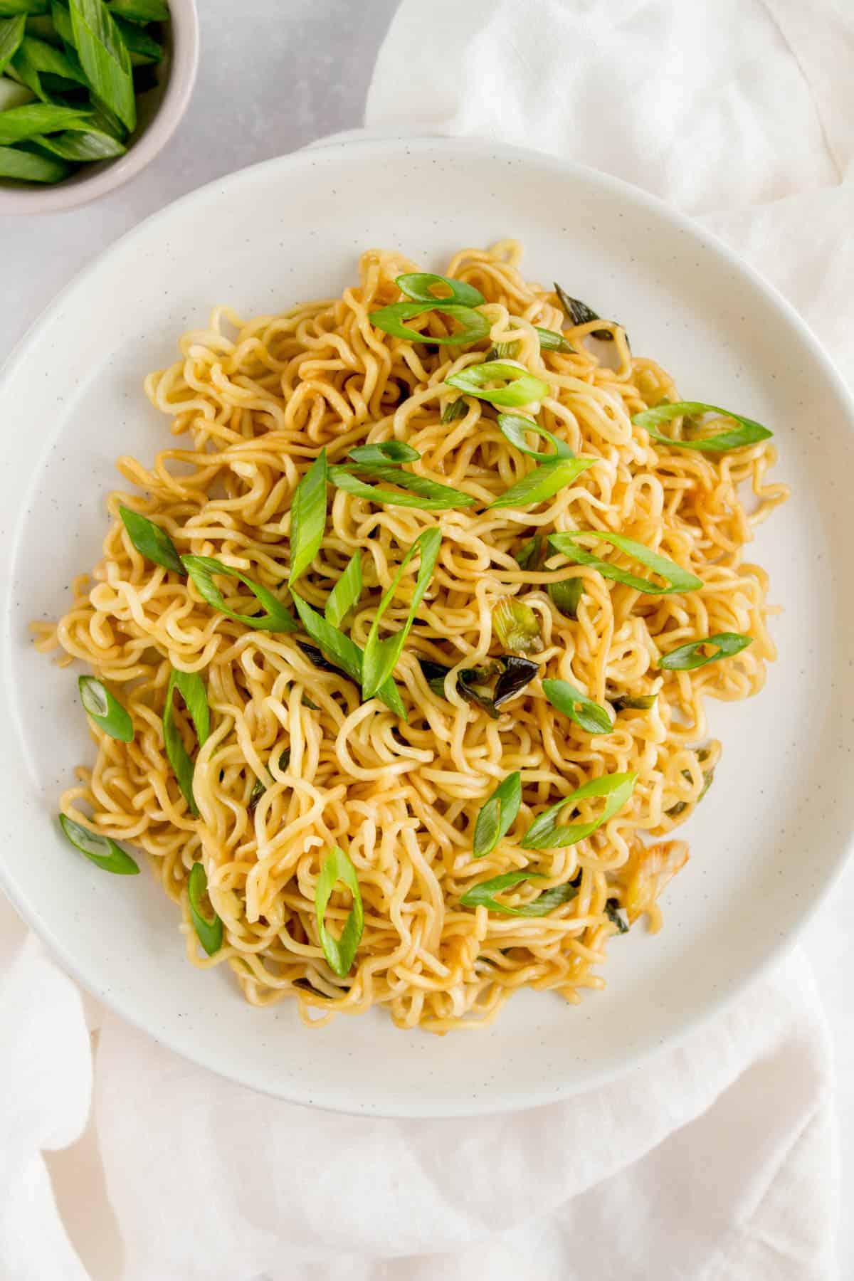 A plate of scallion noodles with sliced scallions as garnish.