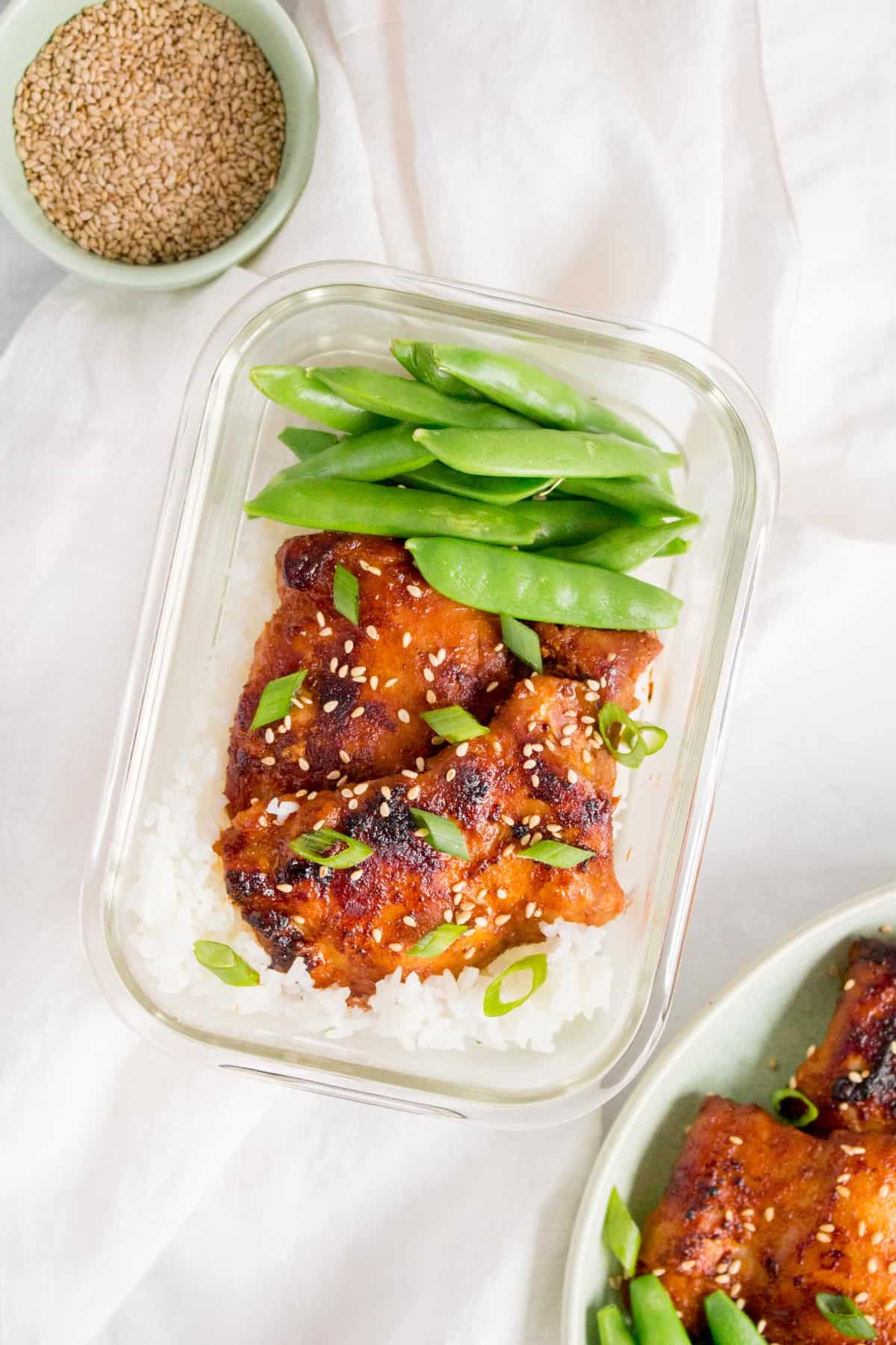 Meal prep container with rice, Korean chicken thighs, and snap peas.
