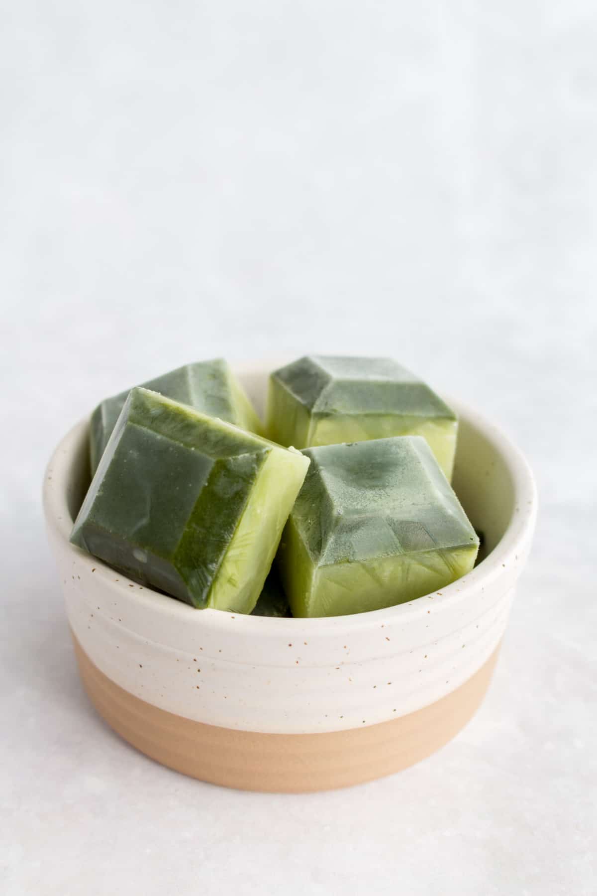 Matcha ice cubes in a small container.