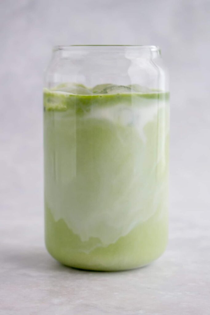 Matcha added to the milk in a glass.