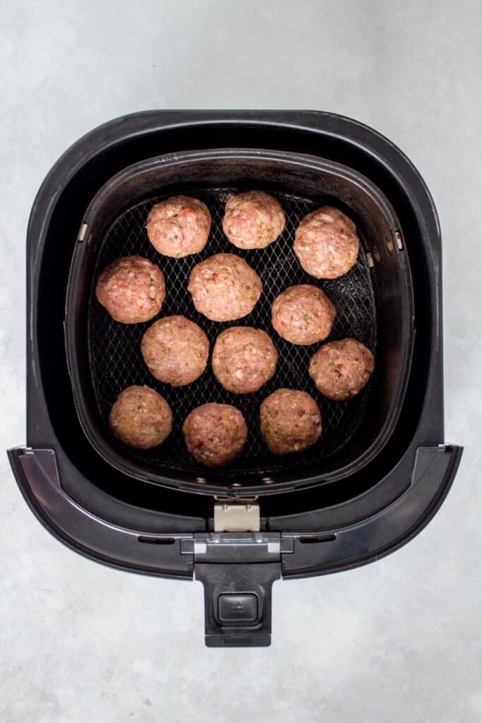 Meatballs in an air fryer basket.