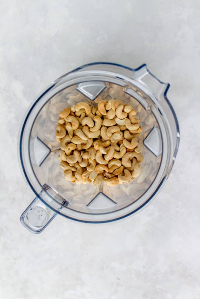 A vitamix with four cups of roasted cashews.