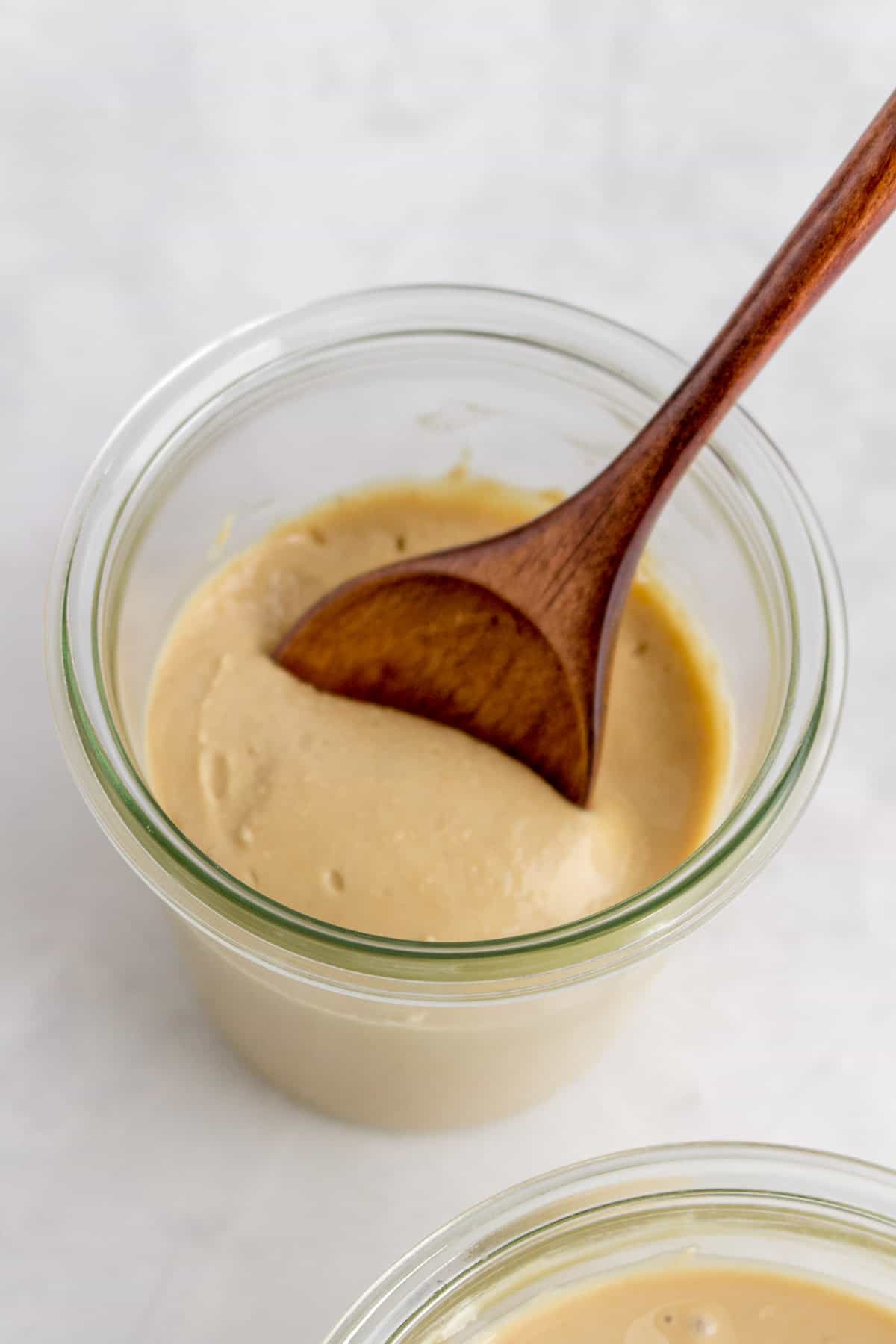 A wooden spoon scooped into a jar of cashew butter.