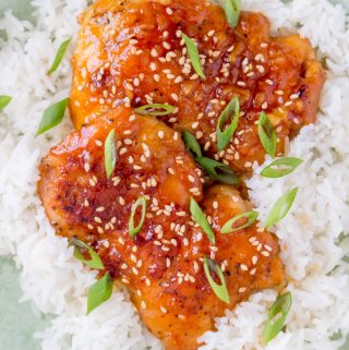 Close up of two spicy chicken thighs over rice.