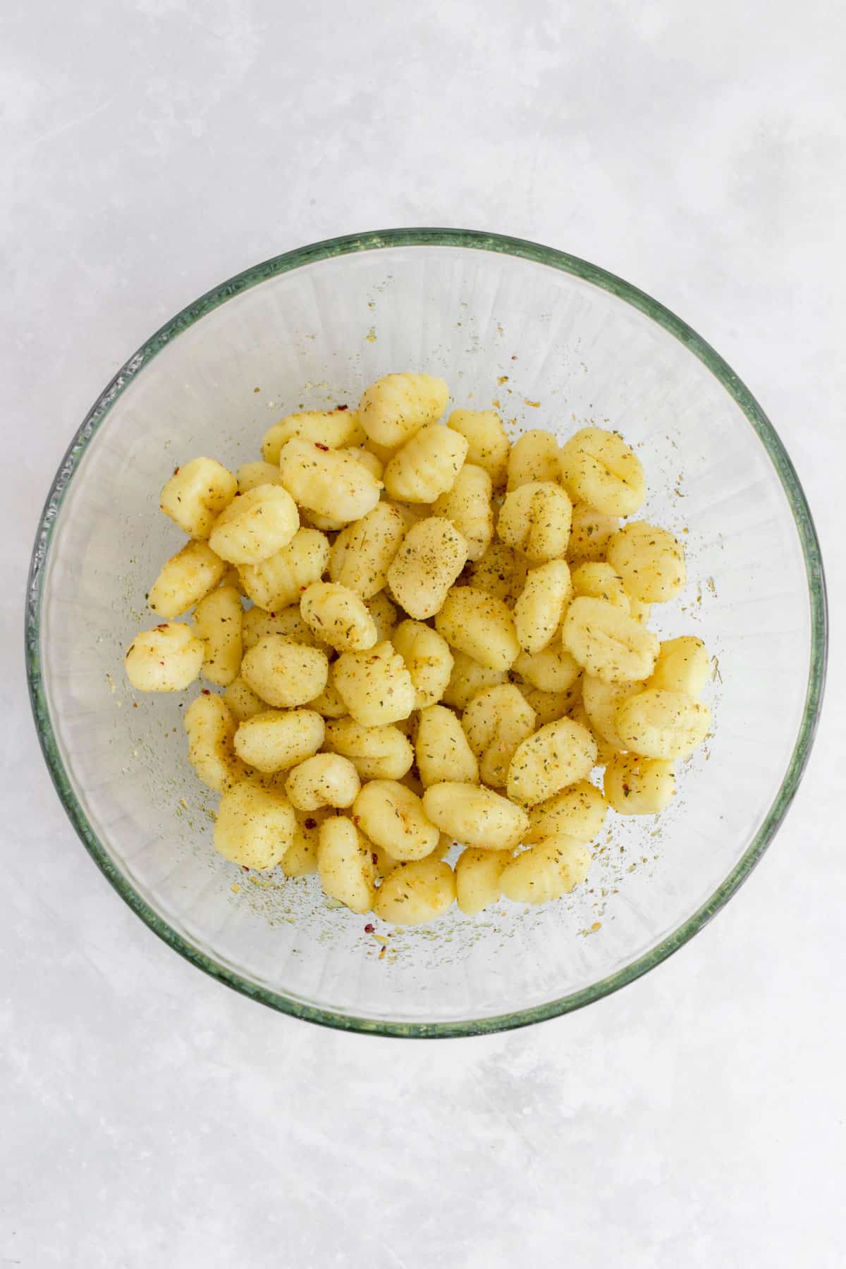 Overhead view of a bowl of gnocchi tossed in olive oil and seasonings.