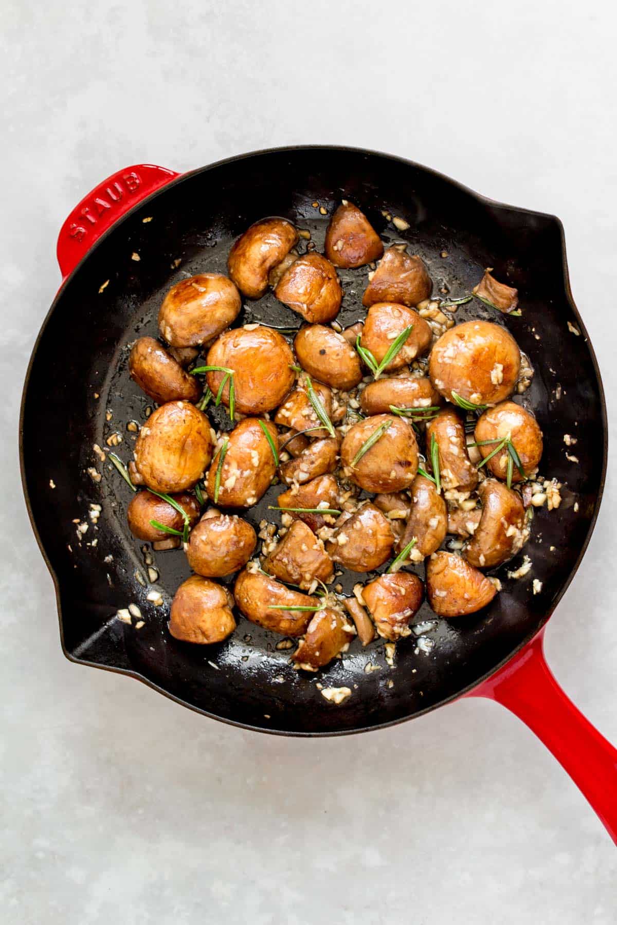 A staub frying pan with garlic butter mushrooms with rosemary.