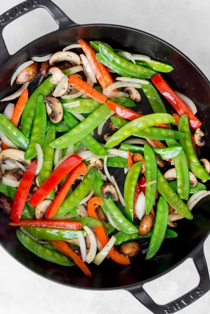 Vegetables stir frying in a large pan.