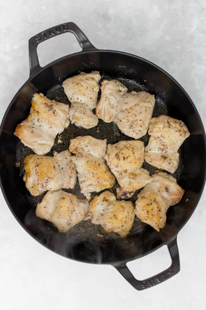 Seared chicken thighs in a pan.